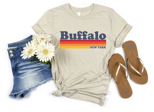 Unisex Vintage Buffalo Shirt in tan paired with light denim shorts and tan sandals.