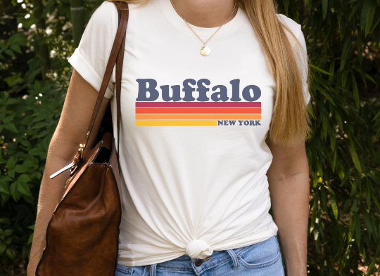 Unisex Vintage Buffalo Shirt in white paired with light wash jeans and a brown leather bag.